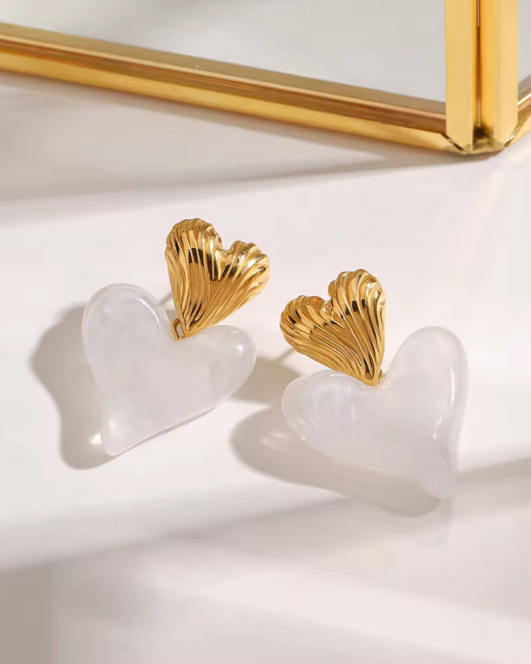 Love on Top earrings in white and gold, featuring a sculpted double heart drop design. Luxury statement jewelry for women that blends elegance, romance and bold fashion vibes.