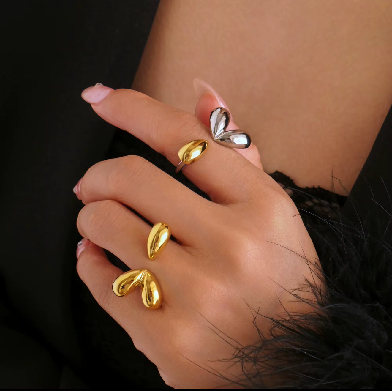 Lifestyle photo of the Modern Muse Rings in polished gold and silver. Sculptural open band statement rings styled on a woman's hand with modern luxury vibes.