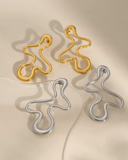 Abstract Baddie Earrings in gold and silver shown together. A bold lifestyle jewelry photo highlighting luxury sculptural hoops for women with modern artsy style. 