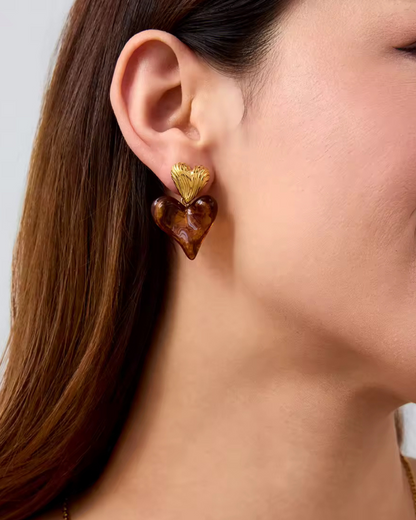 Close-up of a woman wearing the Love on Top Earrings with gold-tone heart studs and amber resin heart drops — from I Am Luxury Accessories Boutique.