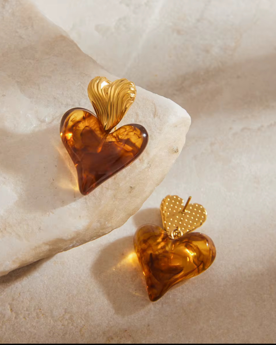 Love on Top Earrings featuring gold-tone heart studs with amber resin heart drops, displayed on stone surface — from I Am Luxury Accessories Boutique.