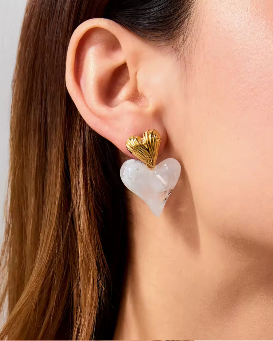 Close-up of a woman wearing the Love on Top Earrings in white resin and gold, a bold statement accessory that instantly elevates any outfit with modern elegance.