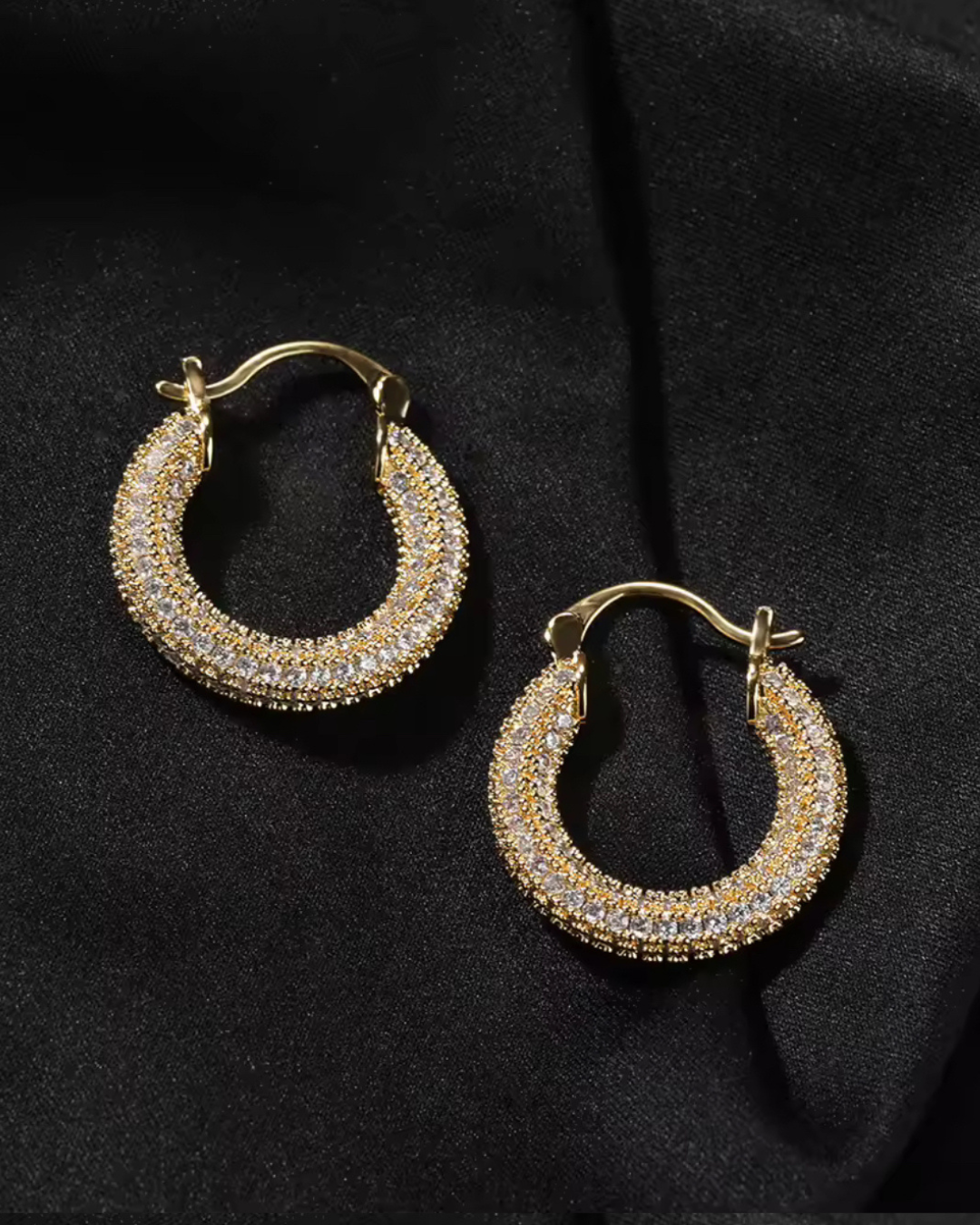 Gold Main Character Earrings with CZ stones, chunky hoop design styled for everyday wear, displayed on a black fabric background.
