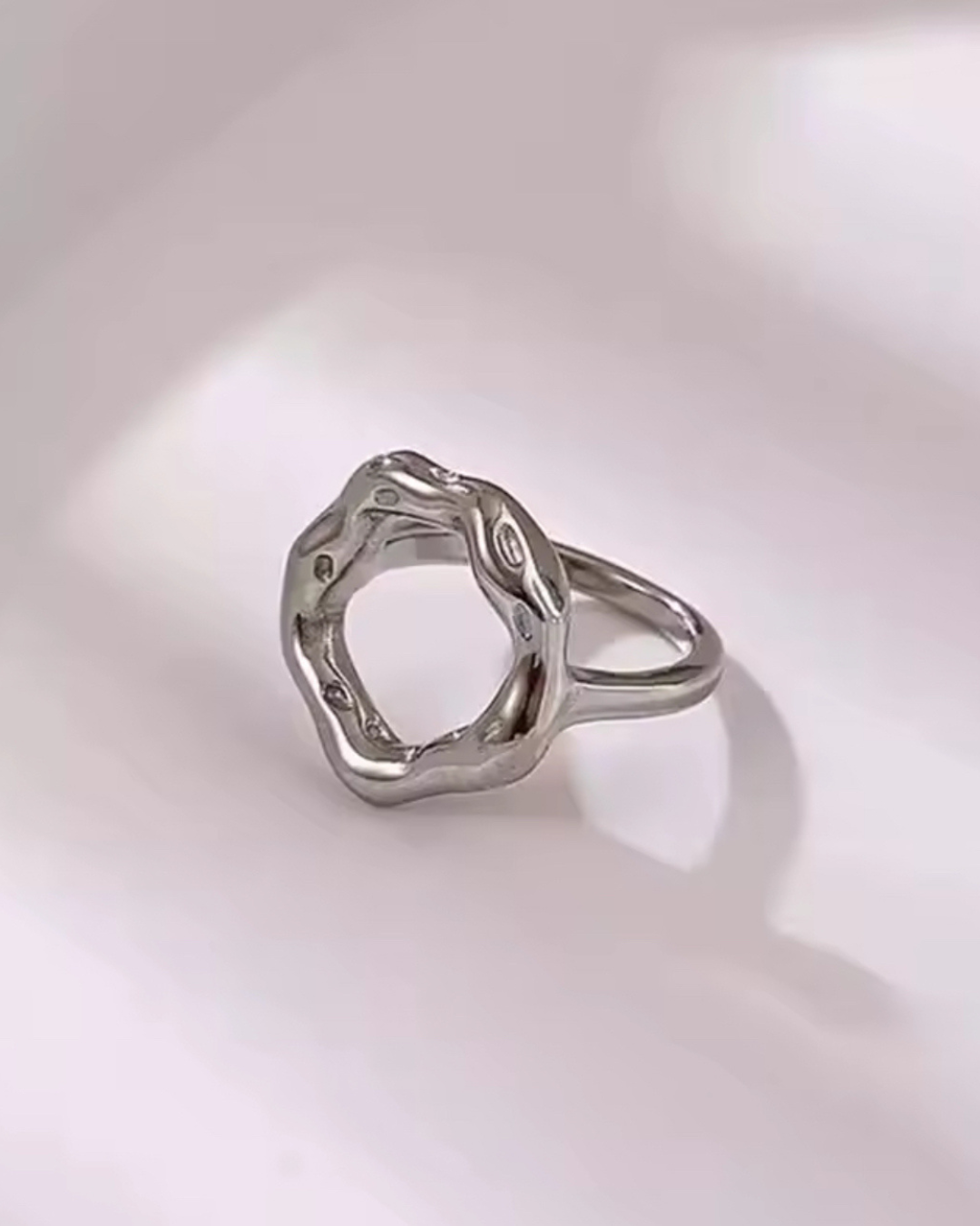 Minimalist silver Opulence Ring for women, stainless steel with circle-shaped open design, hypoallergenic jewelry shown in side view on white background. 