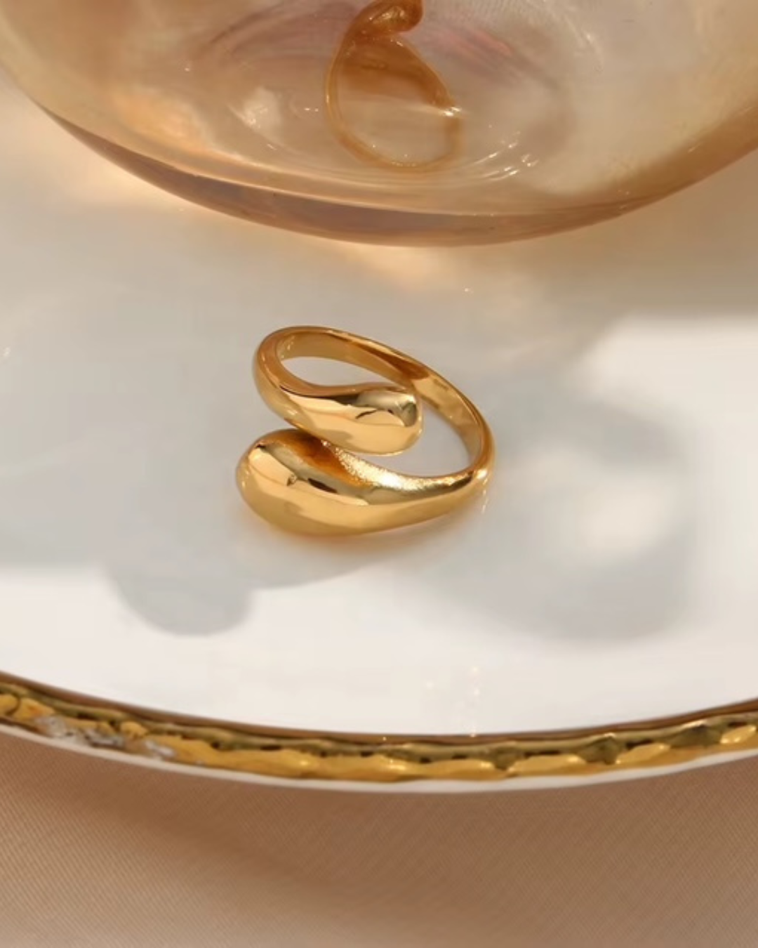 A sculptural gold ring styled on a glass dish with elegant minimalism--perfect for women who love statement pieces with everyday luxury vibes. 