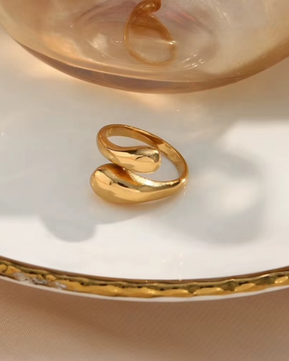 A sculptural gold ring styled on a glass dish with elegant minimalism--perfect for women who love statement pieces with everyday luxury vibes. 