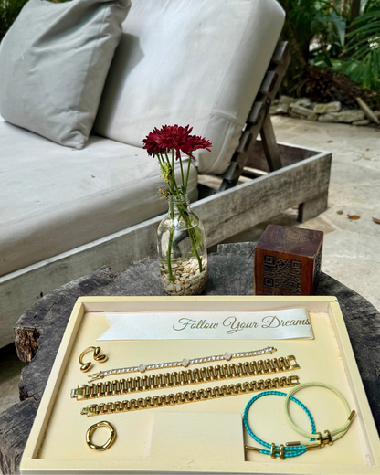 Lifestyle display of SneakyLink Bracelets in thick and thin styles, paired with the Stacked Like a Horse Bracelets, Modern Muse Ring, and Wave Runner Ring, arranged on a tray with the phrase “Follow Your Dreams” beside a vase of flowers.