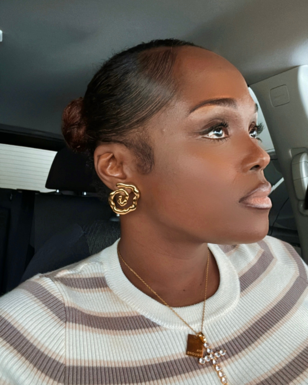 Woman leaving brunch wearing Twist of Faith Earrings in gold with a striped top, layered I Am Enough Necklace, and Faithfully Fine Cross Necklace — a look that transitions effortlessly from brunch to church.