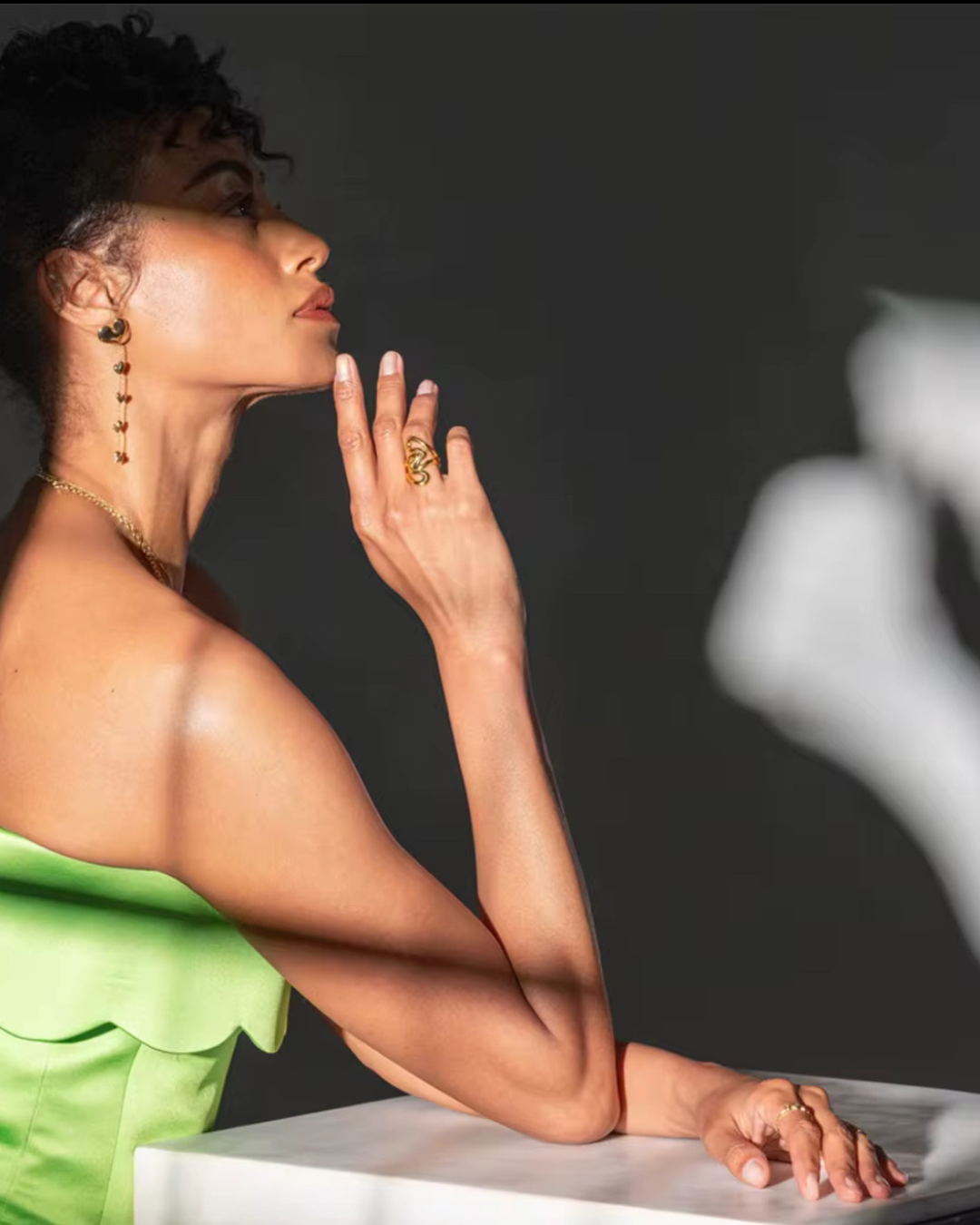 Woman in a green strapless outfit posing in profile, wearing the Untamed Ring in mixed gold and silver for a bold, editorial statement look.