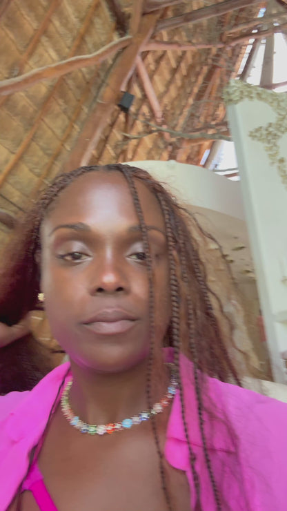 Lifestyle video of a woman wearing the In Full Bloom Necklace with multicolor CZ floral clusters, styled in a pink top and blazer, showcasing bold, feminine jewelry.