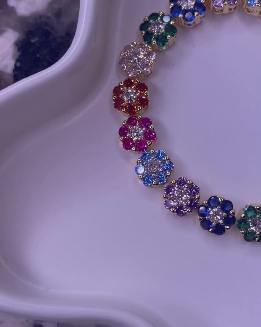 Video pan of the In Full Bloom necklace and bracelet set on a white tray set on a marble countertop.