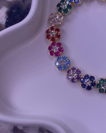 Video of the In Full Bloom Bracelet and matching necklace – multicolor CZ floral cluster jewelry in 18k gold and silver stainless steel, shown on a white tray with a marble background, as the camera pans in a circle for a full view.
